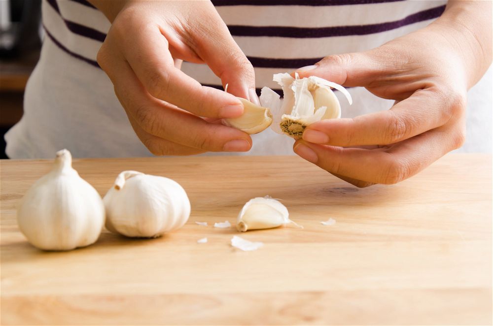 Hands peeling garlic cloves
