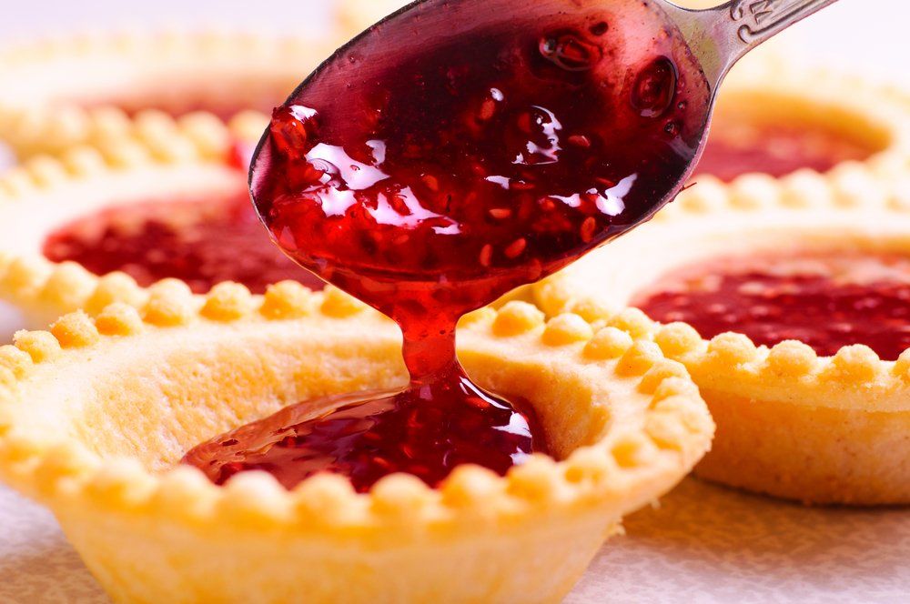 Raspberry sauce pouring into tart cases