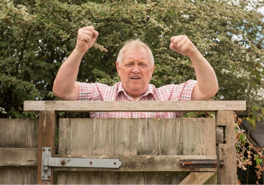 man-shaking-fist-over-garden-fence