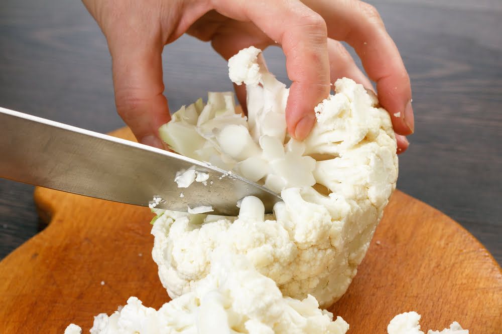 Hand chopping cauliflower with knife