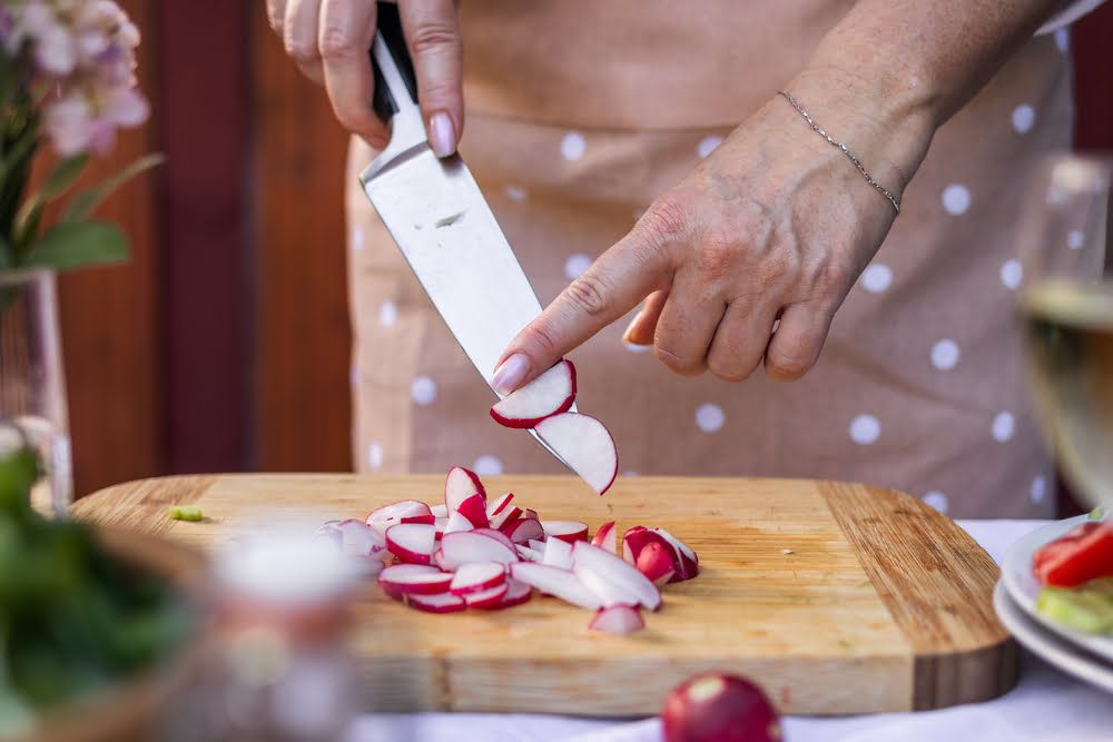 Person slicing radishes on chopping board