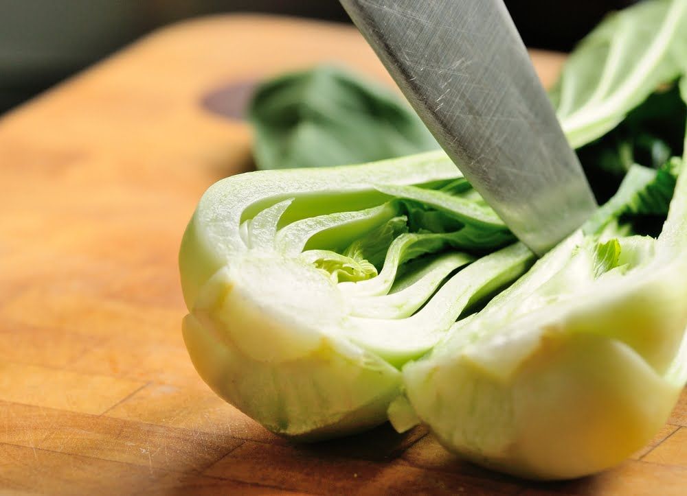 Knife cutting through pak choi